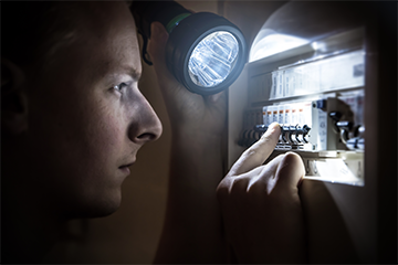 Image of a person checking their fuse box in the event of a power cut 