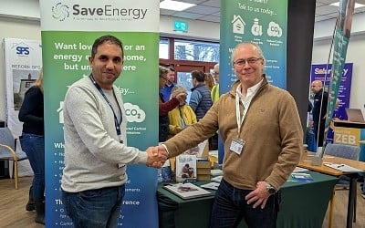 Two men shaking hands in front of stand showing leaflets from SSEN and SaveEnergy