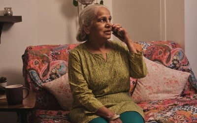 A customer registered for SSEN's priority services sitting on their sofa on the phone receiving help and support