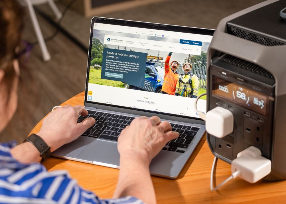 A home battery pack being used to power a laptop and charge a mobile phone A home battery pack being used to power a laptop and charge a mobile phone