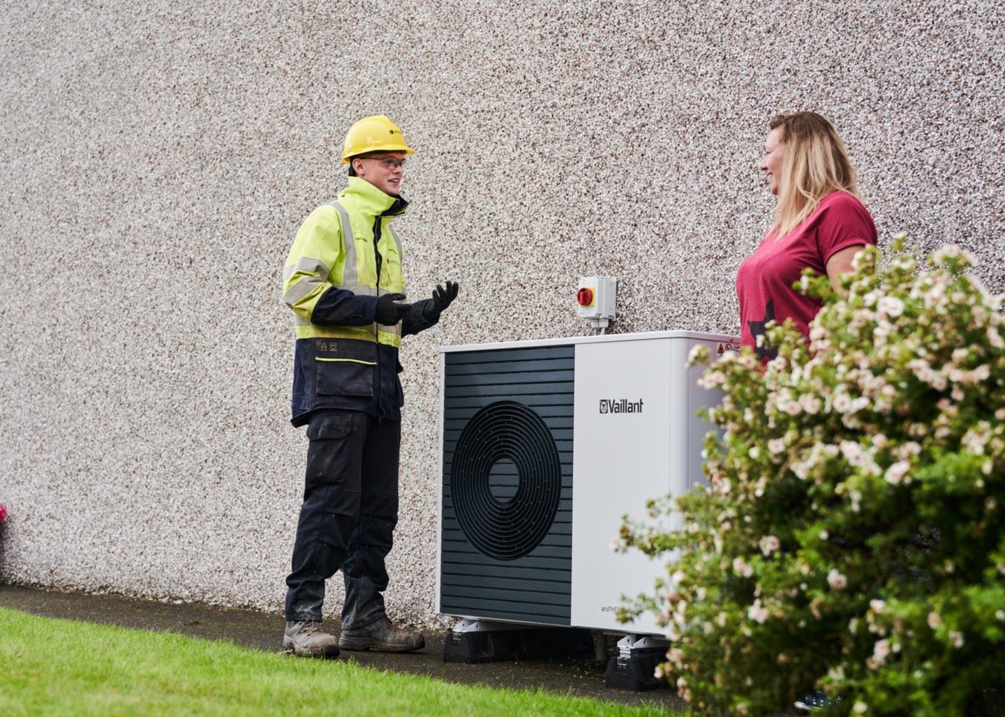 An SSEN engineer and a homeowner standing by a heat pump on the side of a property