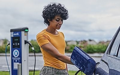 A motorist using an EV charger on the public network in a car park