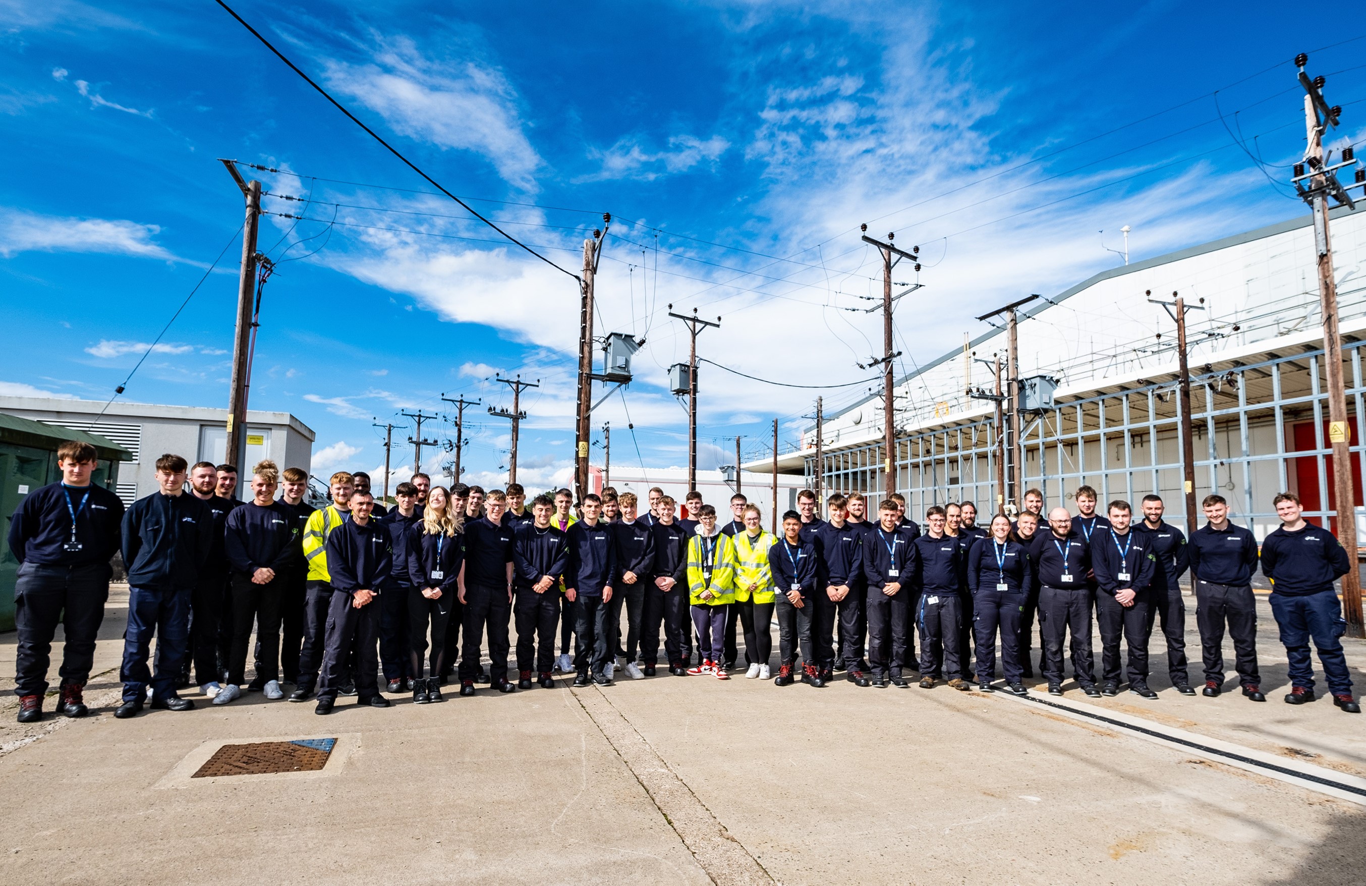 Group of apprentices standing outside in front of electricity network