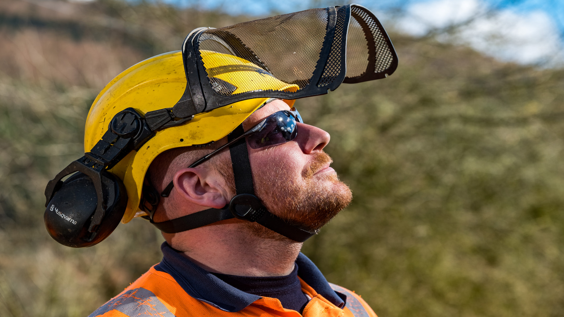 Man in hard hat, visor and sunglasses looking at the sky