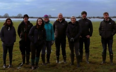 Group of people in a field, smiling and facing the camera 