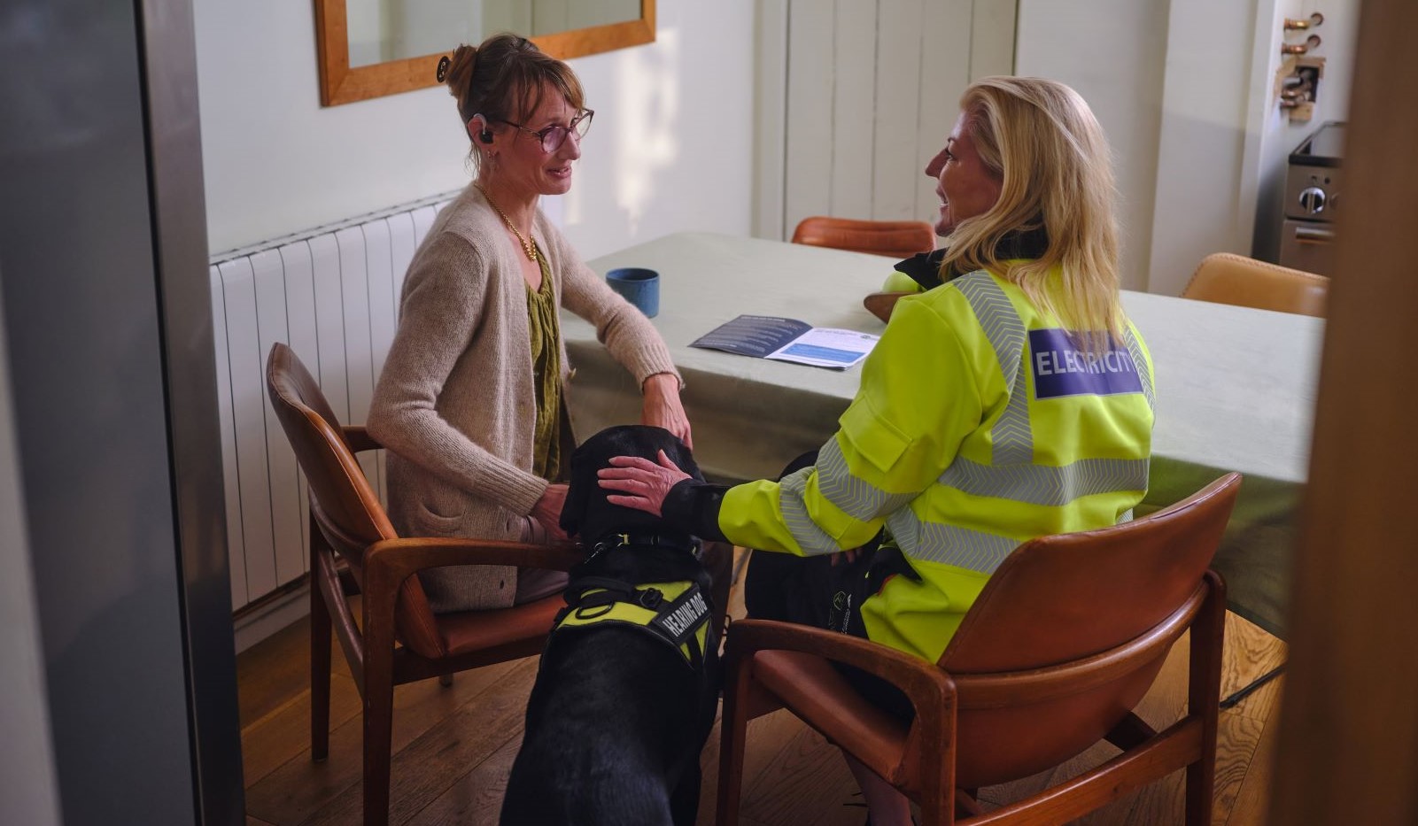 Two women and guide dog sitting in kitchen