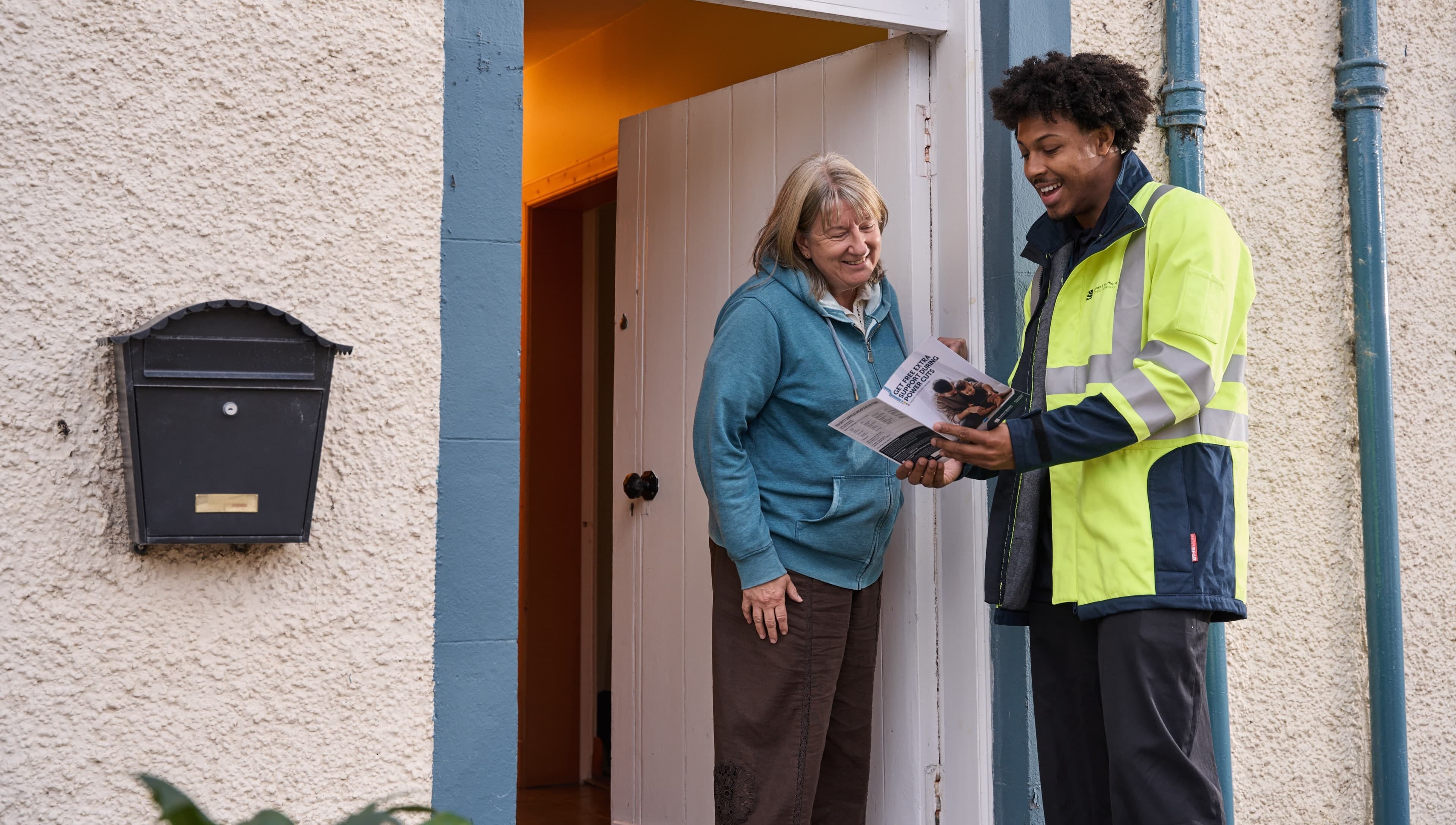 Young engineer showing PSR booklet to customer at their front door.