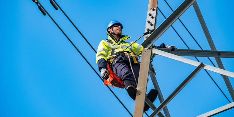 Engineer climbing transmission tower smiling