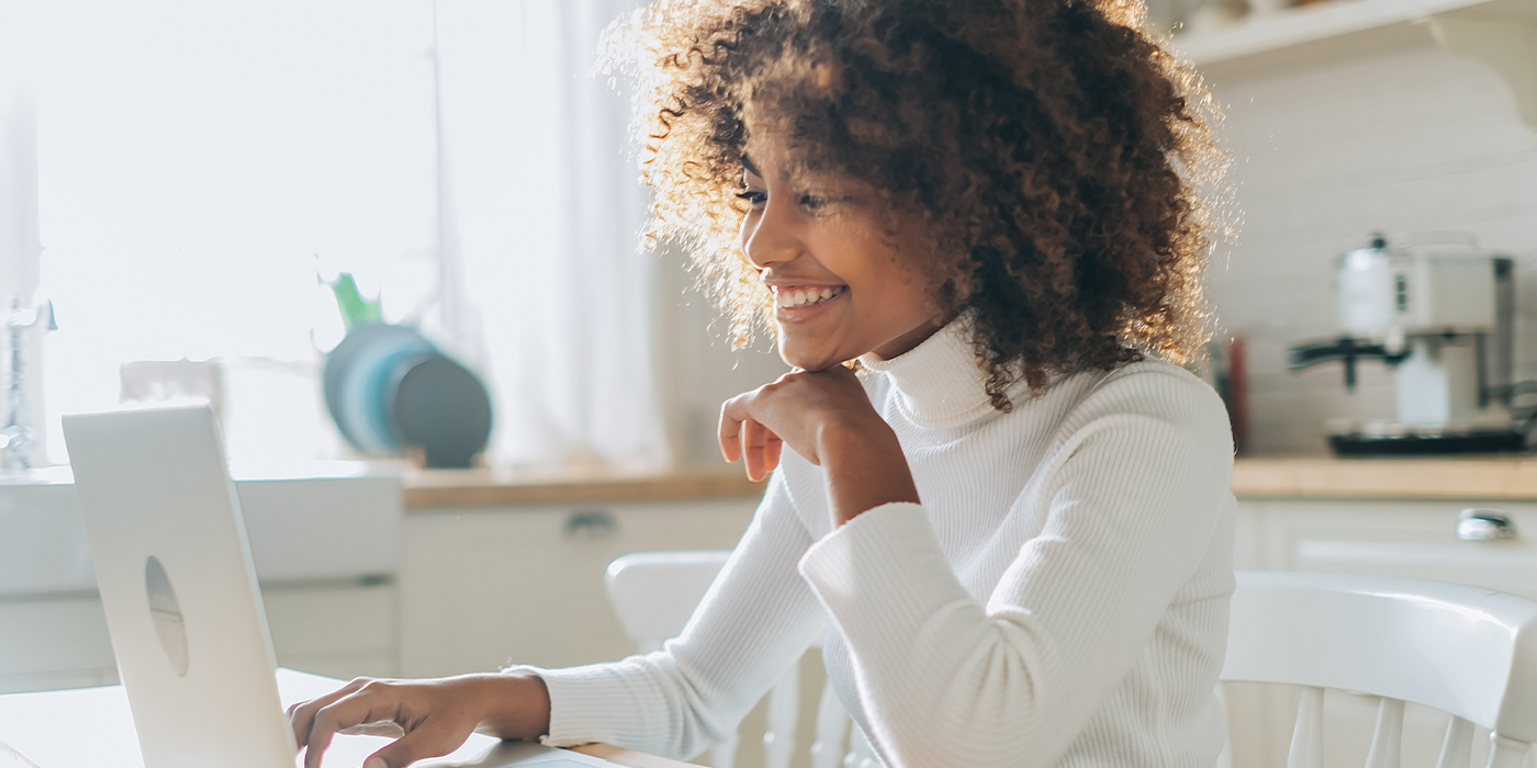 Woman looking at laptop smiling in kitchen
