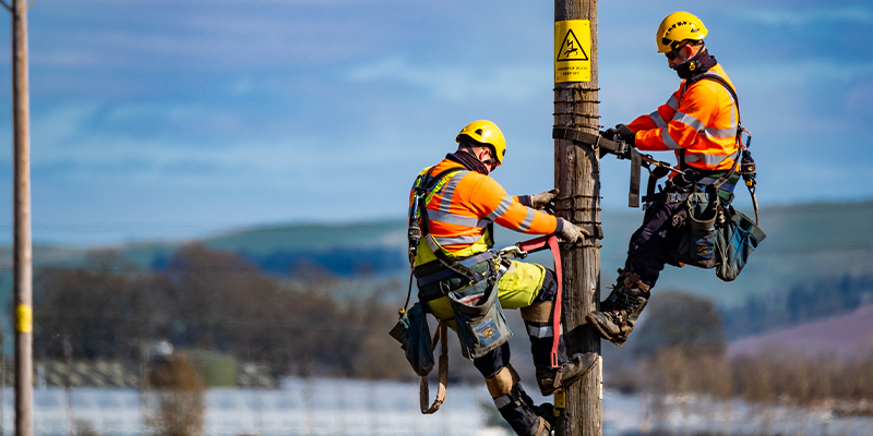 SSEN Linesmen working in Blairgowrie, climbing up a wooden pole 