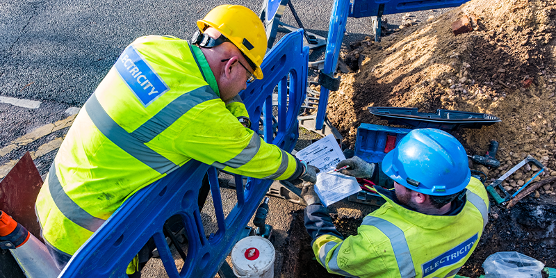 Image shows SSEN engineers looking at paperwork while carrying out underground cable works 