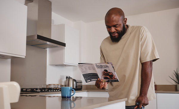 Customer with walking stick reading PSR leaflet in kitchen