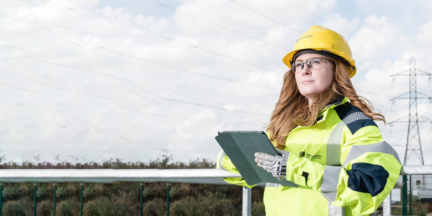 Female engineer outdoors with clipboard - tower in background