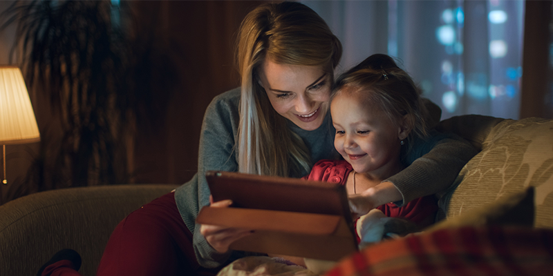 Image of mother and daughter looking an tablet and smiling 