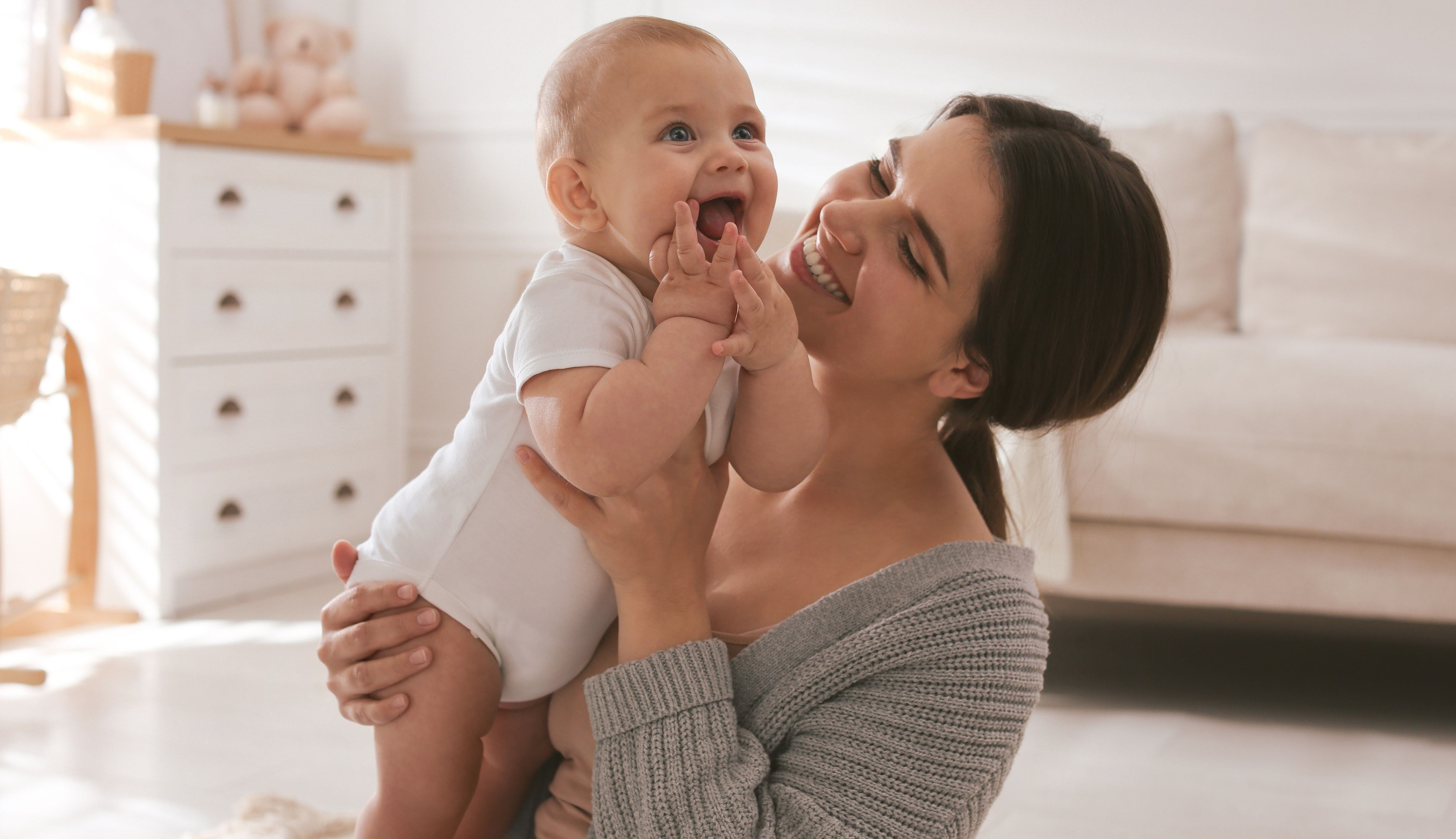 Mother holding baby, smiling.