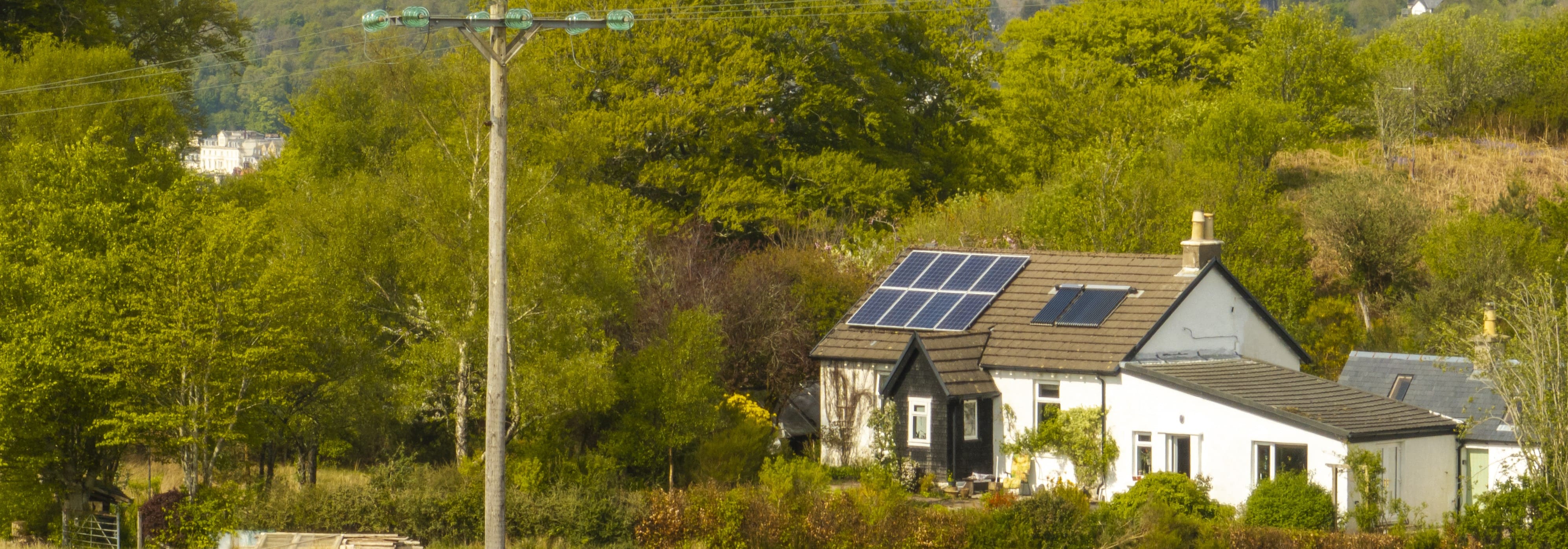 Picture of home with green landscape and power line in view.