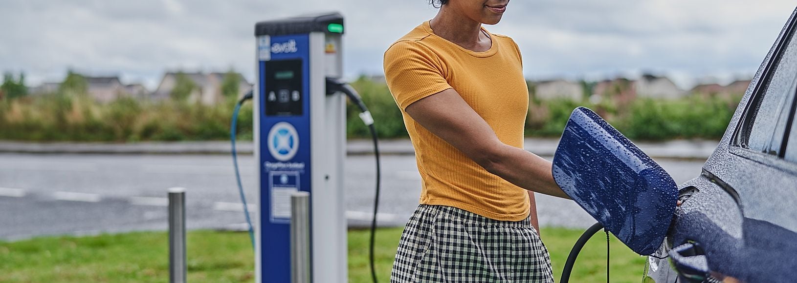 A motorist using an EV charger on the public network in a car park