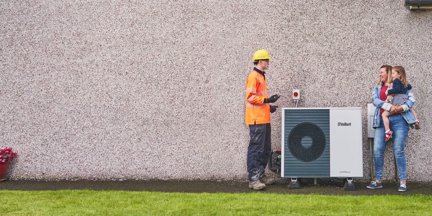 An SSEN engineer with a homeowner by a heat pump on the side of her property